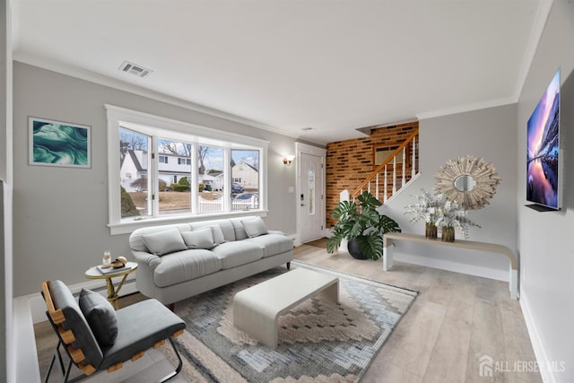 living area featuring visible vents, baseboards, wood finished floors, stairway, and ornamental molding