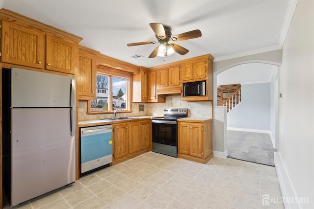 kitchen featuring a sink, arched walkways, stainless steel appliances, light countertops, and visible vents