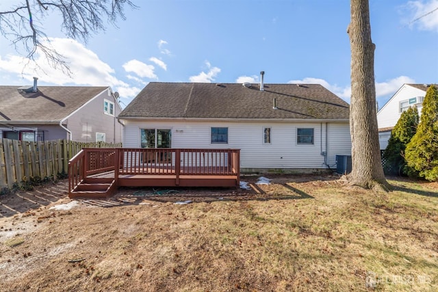 back of house with fence, central air condition unit, a wooden deck, a lawn, and roof with shingles