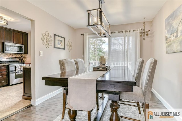 dining area with light wood-style floors, baseboards, and a chandelier
