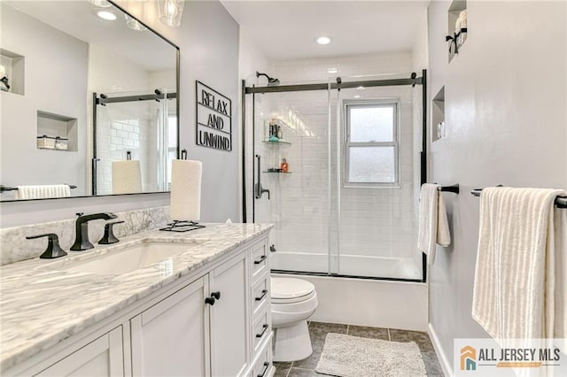 full bath featuring vanity, toilet, combined bath / shower with glass door, and tile patterned flooring