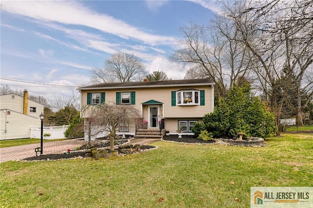raised ranch with a front yard, decorative driveway, and a chimney