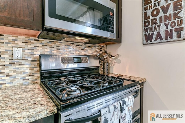 kitchen featuring appliances with stainless steel finishes, tasteful backsplash, dark brown cabinetry, and light stone countertops