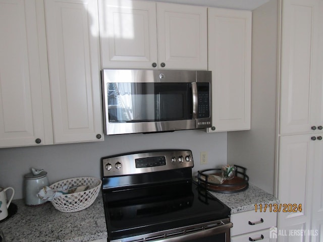 kitchen featuring light stone countertops, appliances with stainless steel finishes, and white cabinets