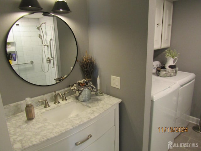 full bath with washing machine and dryer, a tile shower, and vanity