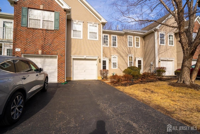 view of front of home with brick siding, driveway, and a garage