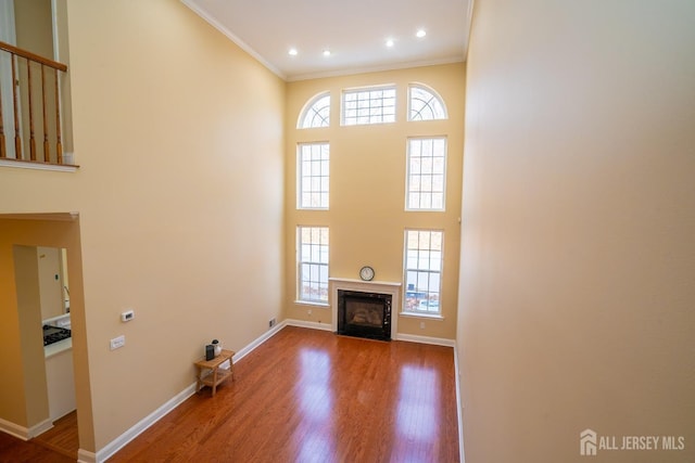 unfurnished living room featuring ornamental molding, wood finished floors, and a healthy amount of sunlight