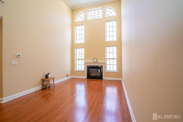 unfurnished living room featuring baseboards, ornamental molding, a wealth of natural light, and wood finished floors