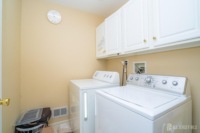 laundry area with visible vents, cabinet space, and washing machine and clothes dryer