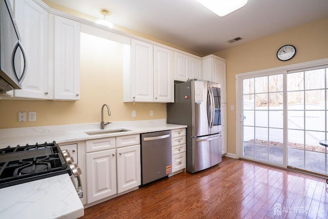 kitchen featuring stainless steel appliances, a sink, white cabinetry, visible vents, and dark wood-type flooring