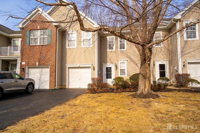 townhome / multi-family property featuring brick siding, driveway, and an attached garage