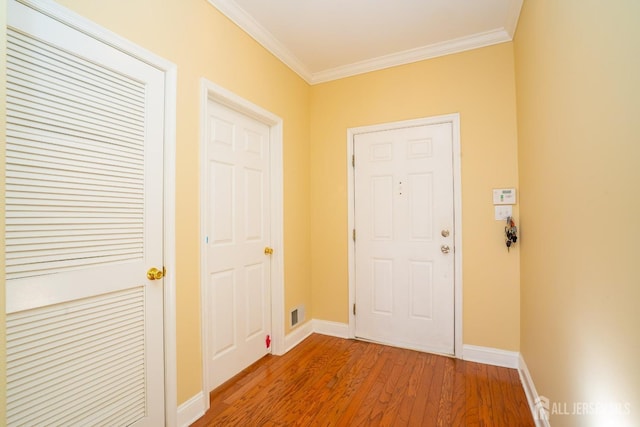 foyer featuring baseboards, visible vents, wood finished floors, and ornamental molding