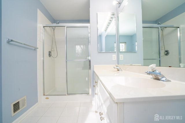 full bath featuring a shower stall, a sink, double vanity, visible vents, and tile patterned floors