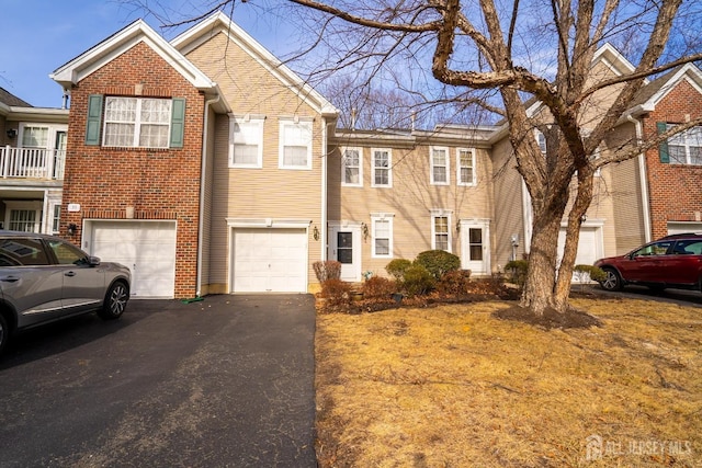 multi unit property featuring a garage, brick siding, and driveway