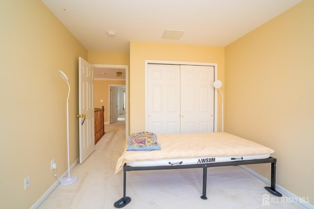 bedroom with a closet, light carpet, and baseboards