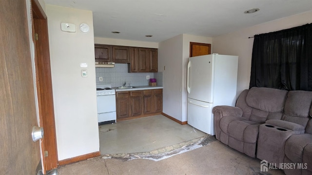 kitchen featuring white appliances, open floor plan, a sink, tasteful backsplash, and baseboards