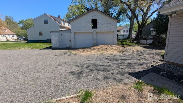 view of side of home featuring an outbuilding, a detached garage, and fence