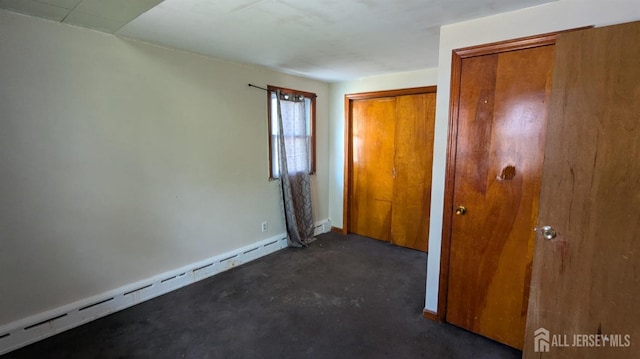 unfurnished bedroom featuring a baseboard radiator, concrete flooring, and baseboards