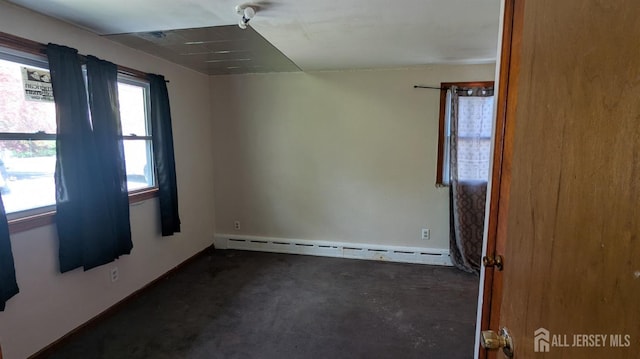 spare room featuring a baseboard heating unit and concrete flooring