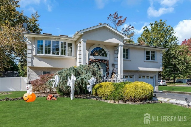 raised ranch featuring a garage and a front yard