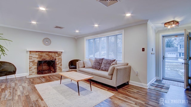 living area featuring visible vents, a fireplace, wood finished floors, and crown molding