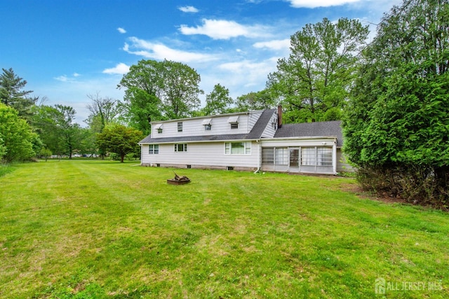 rear view of house with a fire pit and a lawn