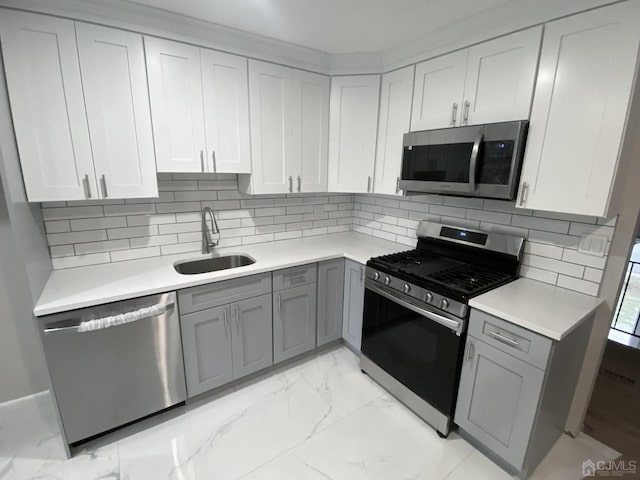 kitchen with backsplash, gray cabinetry, sink, and stainless steel appliances