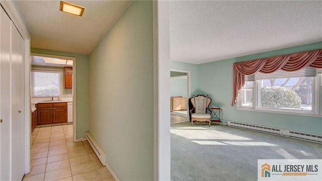 hall with sink, light tile patterned flooring, a textured ceiling, and baseboard heating