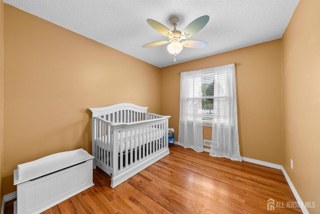 17 4th St, South River, NJ 08882 - bedroom with a textured ceiling, wood finished floors, baseboards, a ceiling fan, and a crib