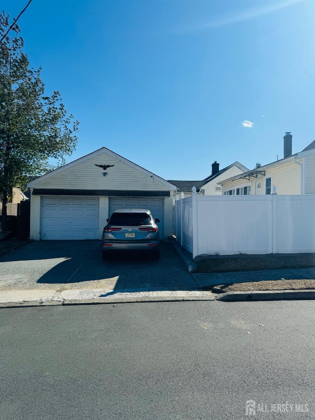 view of front of home featuring fence, a garage, and an outbuilding