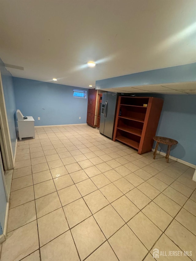 finished below grade area with refrigerator with ice dispenser, recessed lighting, and light tile patterned flooring