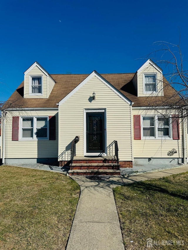 new england style home with crawl space, a front yard, and a shingled roof