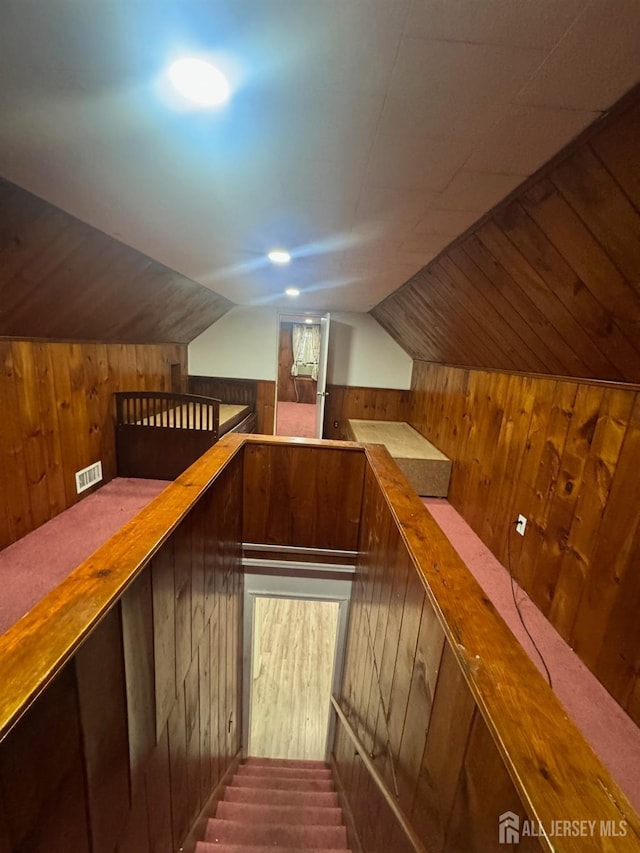 bonus room with wood walls and vaulted ceiling