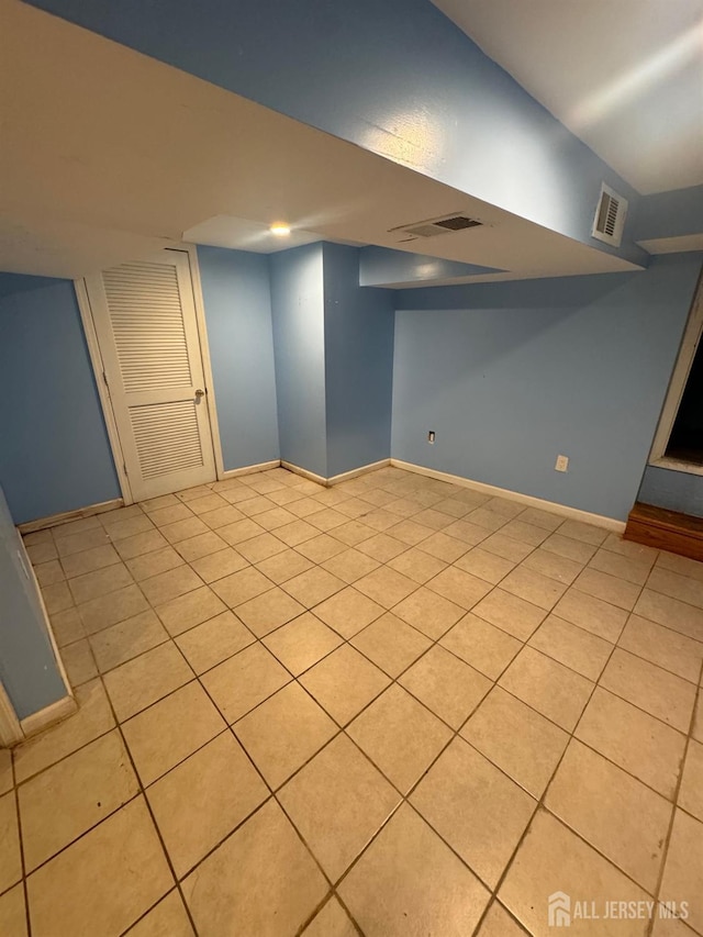 finished below grade area featuring baseboards and light tile patterned flooring