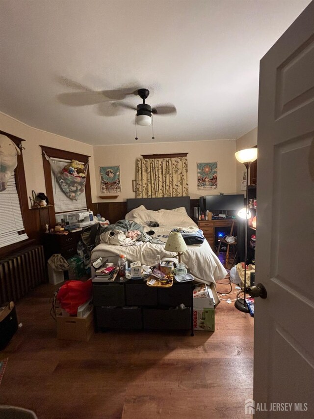 bedroom featuring ceiling fan, radiator heating unit, and hardwood / wood-style floors