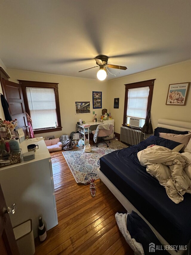 bedroom featuring ceiling fan, radiator heating unit, and hardwood / wood-style floors