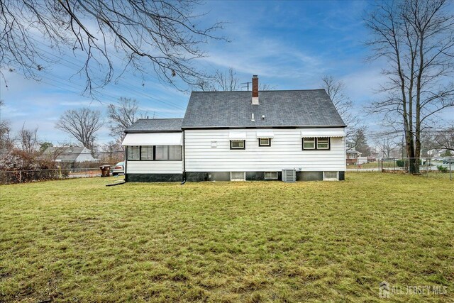 back of house with central air condition unit and a yard