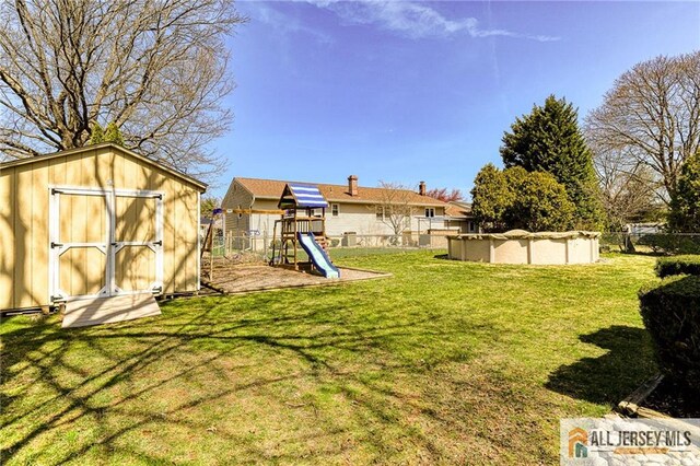 35 Outcalt Rd, Edison, NJ 08817 - view of yard featuring a storage shed, an outbuilding, fence, a fenced in pool, and a playground