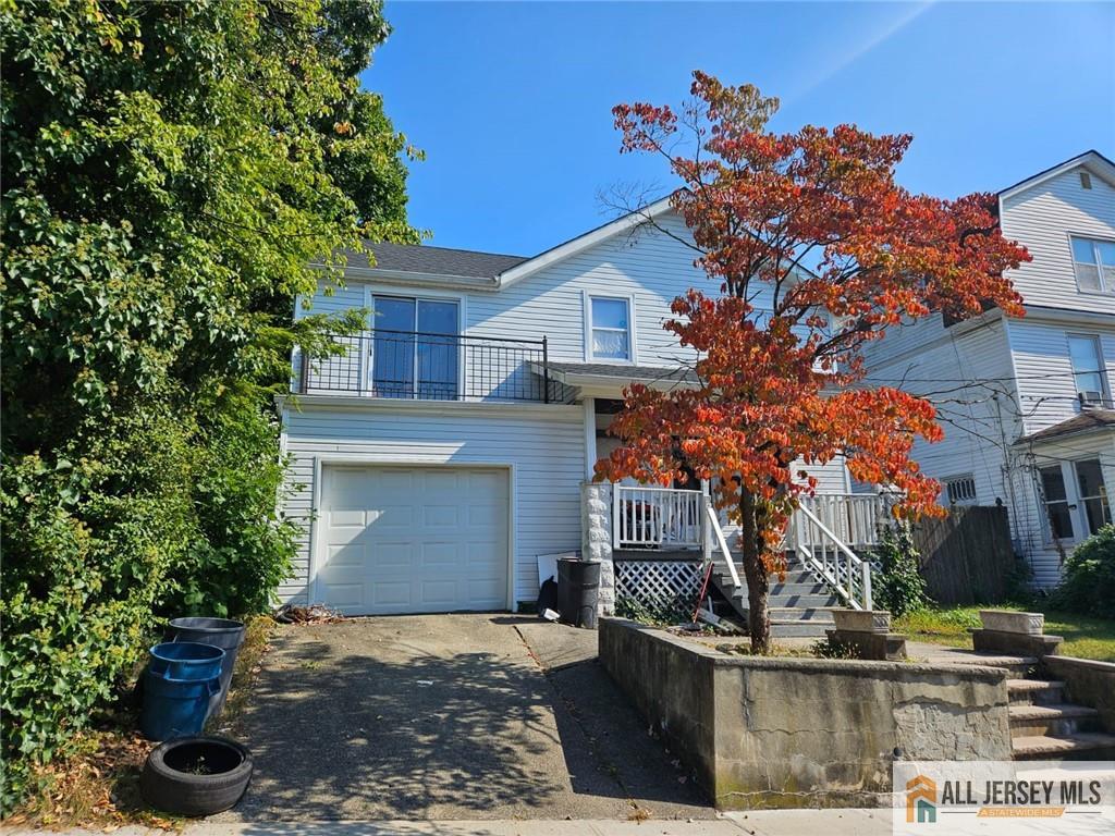 view of front of house with a balcony, an attached garage, and driveway