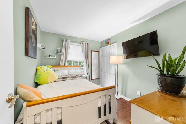 bedroom with a closet, wood finished floors, and baseboards