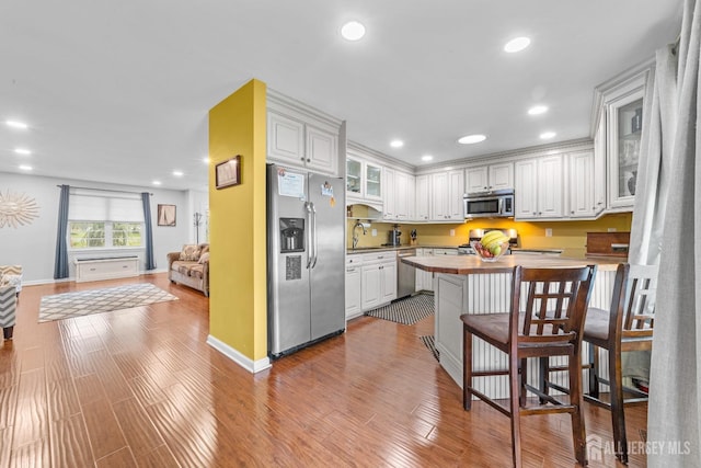 kitchen with glass insert cabinets, white cabinetry, stainless steel appliances, and butcher block countertops