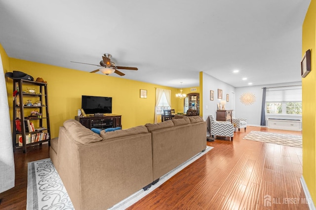 living area with dark wood-style flooring, ceiling fan with notable chandelier, and recessed lighting