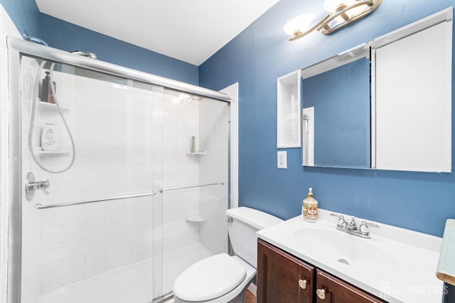 full bath featuring a stall shower, vanity, and toilet