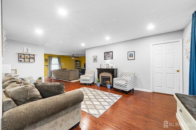 living area with a glass covered fireplace, dark wood-type flooring, a ceiling fan, and recessed lighting
