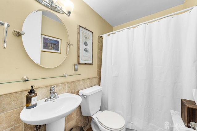 bathroom with toilet, tile walls, a shower with curtain, and a sink