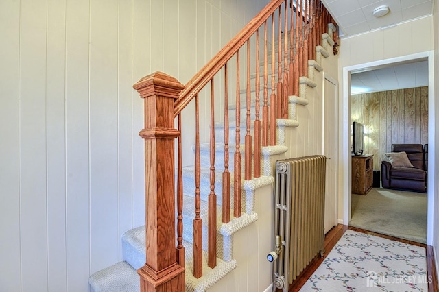 stairs featuring wooden walls and radiator heating unit