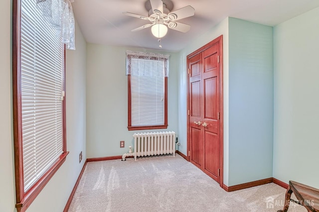 unfurnished bedroom with ceiling fan, radiator, baseboards, and carpet floors