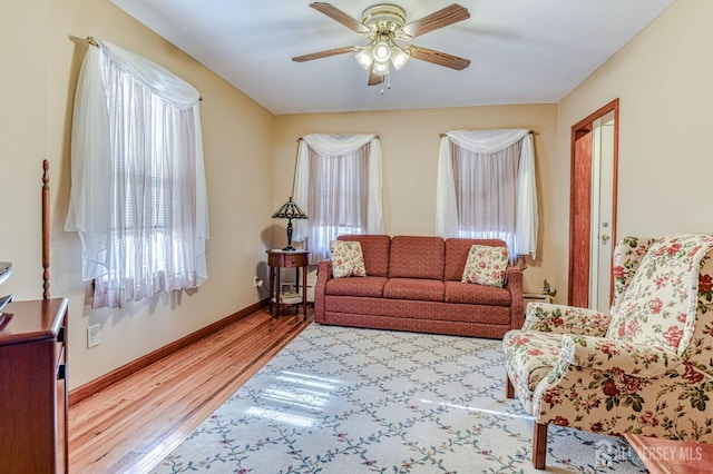 living room featuring ceiling fan, baseboards, and wood finished floors