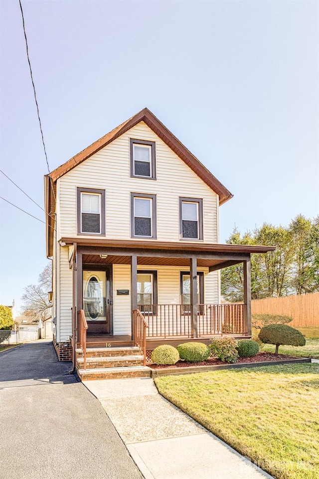 view of front facade featuring a front lawn, fence, and covered porch