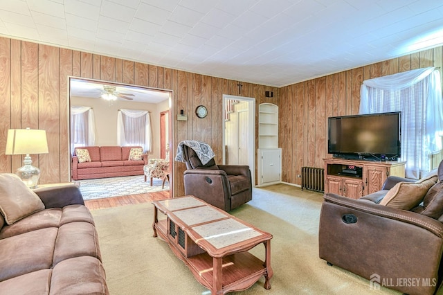 carpeted living area with wood walls and radiator